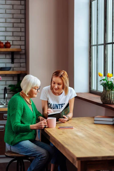 Señora sonriente leyendo la Biblia de Holly mientras pensionista la escucha — Foto de Stock