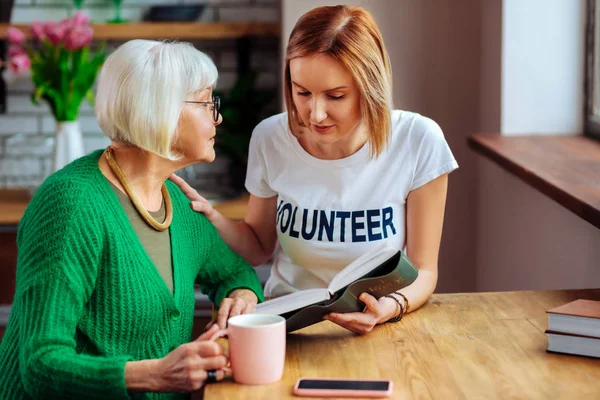 Boeiend twintig-jaar oude vrouw genieten van Bijbel lezen bejaarde gepensioneerde m/v — Stockfoto