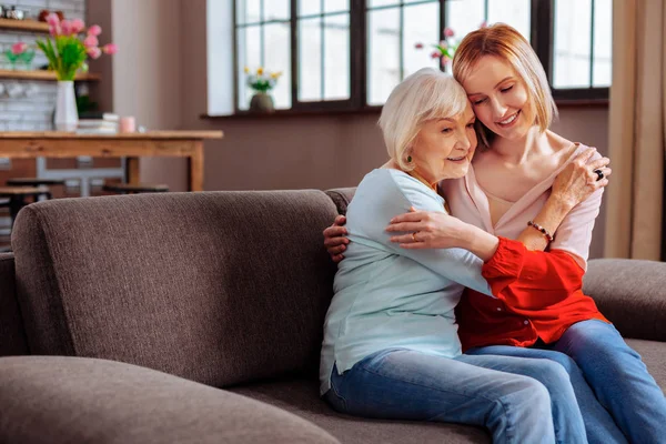 Arresting retired woman tightly embracing granddaughter come to visit her