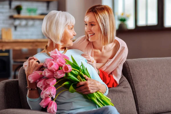 Attractive daughter tenderly looking at elderly d smiling mother