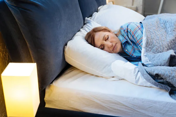 Adult light-haired woman lying with closed eyes covered with warm blanket — Stock Photo, Image