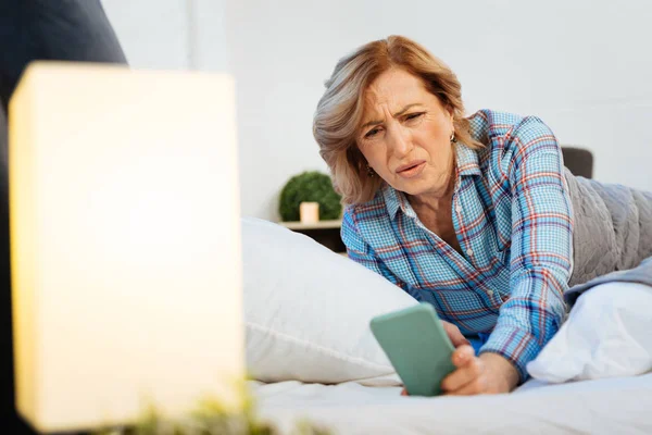 Zavart rövid hajú felnőtt nő keresi a képernyő világos pizsama — Stock Fotó