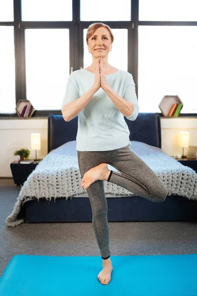 Sorridente signora dai capelli chiari indossa abbigliamento comodo durante l'allenamento di yoga — Foto Stock