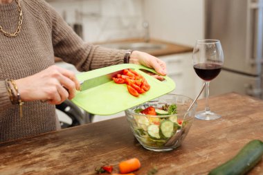 Doğru Bayan bej kazaklı cam kaseye doğranmış domates ekleme