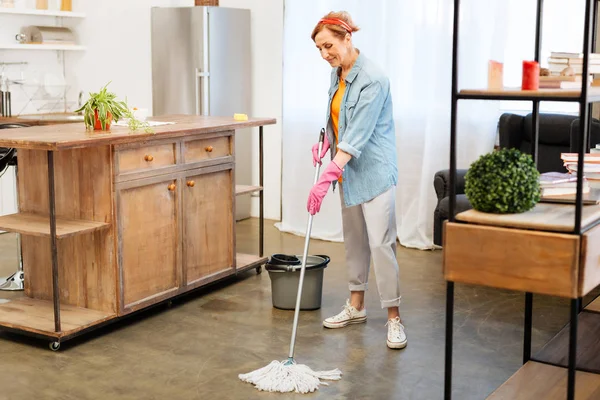 Geballte positive Frau im häuslichen Outfit wäscht Boden mit Wischmopp — Stockfoto