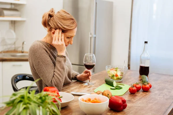 Sad mature woman being alone at home and drinking red wine