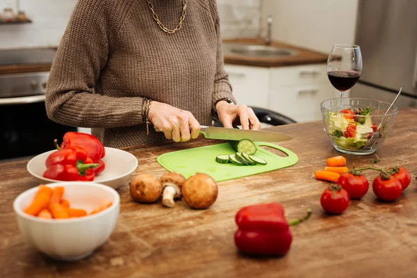 Focused fit mature woman cutting vegetables for healthy salad — Stock Photo, Image