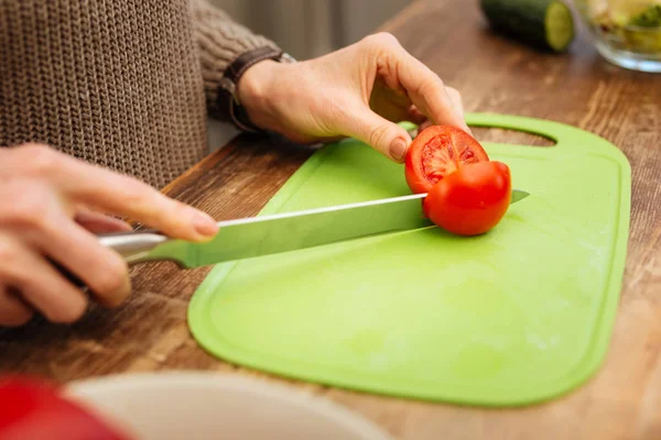 Voksen dame som tilbereder middag med ferske grønnsaker mens hun skjærer dem – stockfoto