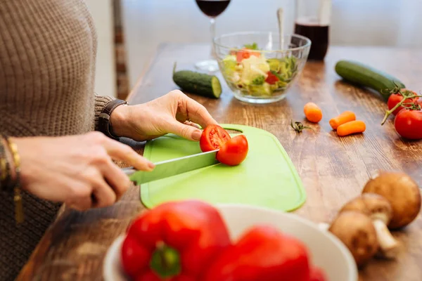 Aangename vrouw uitvoering lange metalen mes en hakken van tomaat — Stockfoto