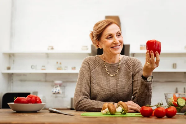 Geniş bir gülümseme biber üzerinde güzel görünümlü memnun ışık saçlı kadın