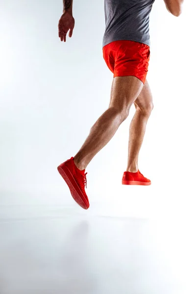 Hravý muž v červeném kraťásky a snickers dělá běh pohyby — Stock fotografie
