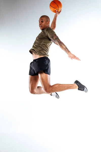Basketball player jumping high holding a ball — Stock Photo, Image
