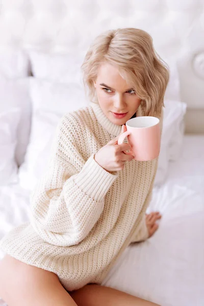 Jonge vrouw dragen beige trui houden van roze kopje thee — Stockfoto