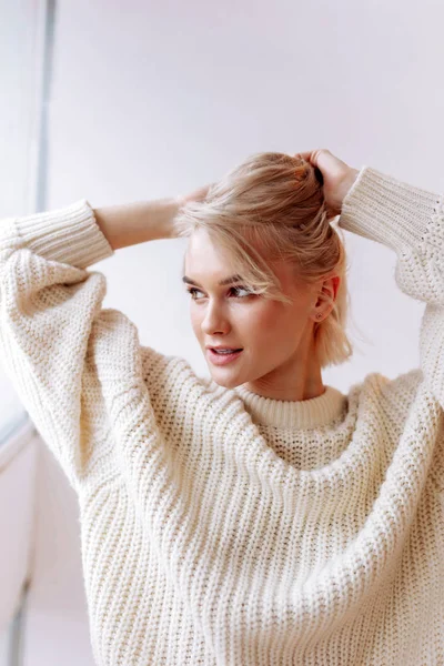 Mujer atractiva con suéter arreglando su cabello en la mañana — Foto de Stock