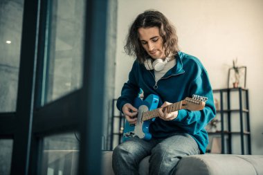 Gitar çalmaya yüzünde dövme ile huzurlu yakışıklı adam