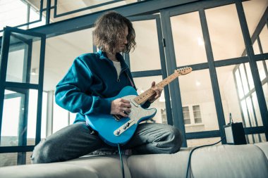 Genç adam gri kanepenin arkasında yatan konsantre