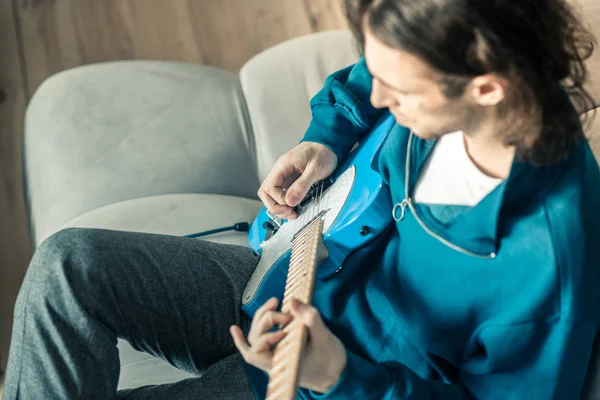 Langhaarige junge Musikerin mit welligem Haar spielt aufmerksam Gitarre — Stockfoto