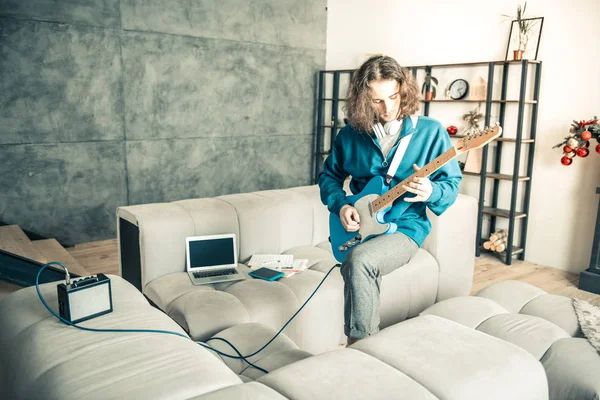 Artistieke jongeman actief spelen op gitaar in het midden van de kamer — Stockfoto