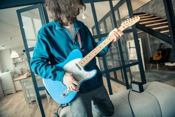 Chico inspirado experimentado con pelo ondulado entrenando sus habilidades de guitarra — Foto de Stock