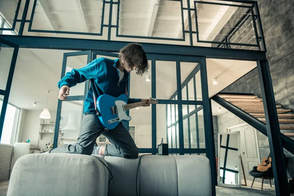 Loco chico de pelo largo tocando en la guitarra electrónica mientras se queda — Foto de Stock