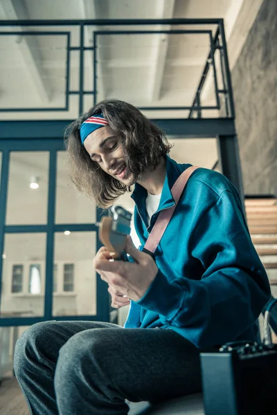 Homem inspirado de cabelos escuros em camisola azul carregando guitarra — Fotografia de Stock