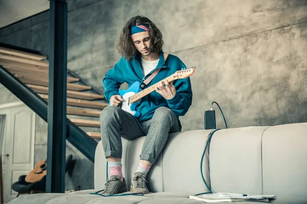 Focused attentive guy in colorful bandana experimenting with his guitar — Stock Photo, Image