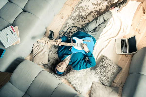 Pensativo joven músico acostado en el suelo cubierto con instrumento musical — Foto de Stock