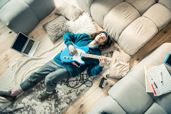 Emotionless moreno de pelo chico tendido en el suelo cubierto con la guitarra en el pecho — Foto de Stock