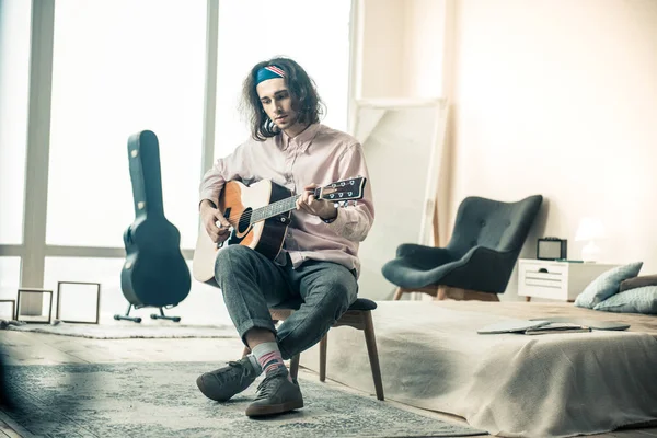 Melancólico músico guapo con cabello ondulado tocando la guitarra acústica — Foto de Stock