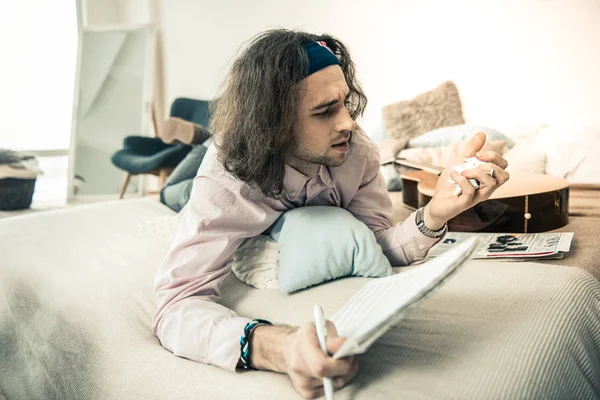 Unsatisfied long-haired guy compressing page from his personal album