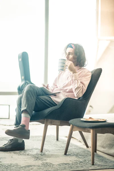 Pensativo hombre de pelo largo en traje elegante beber té mientras descansa — Foto de Stock