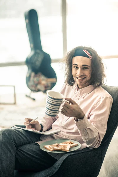 Joven contento mostrando su amplia sonrisa mientras almorza — Foto de Stock