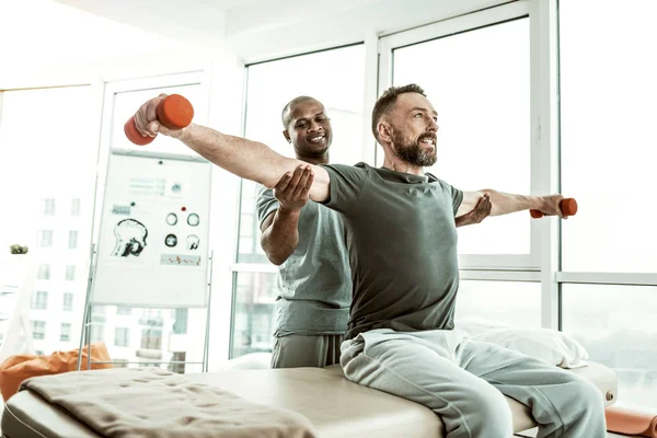 Alegre masculino pessoa levantando halteres com prazer — Fotografia de Stock