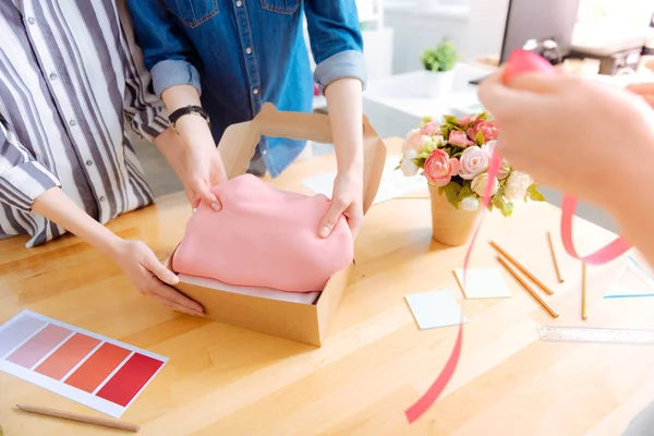 Competent tailor putting pink cloth into box