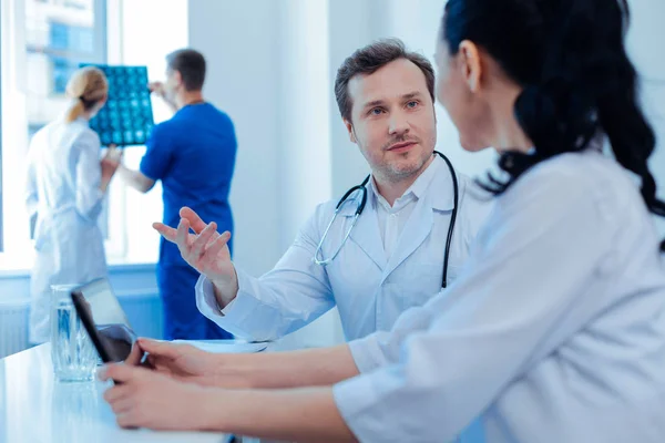 Aufmerksame Ärztin hört seinem Assistenten zu — Stockfoto