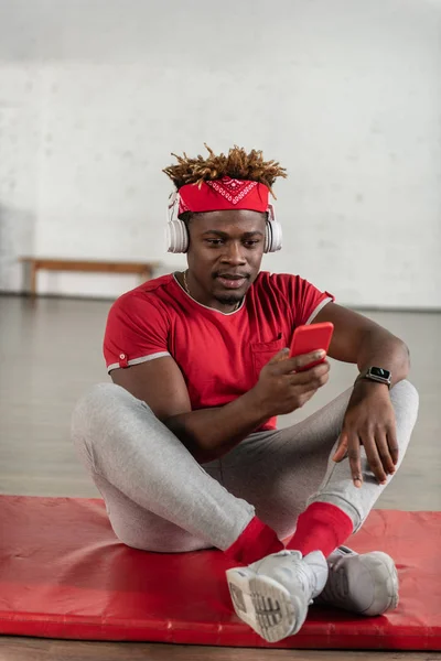 Homem em forma de pele escura concentrado sentado no tapete esportivo — Fotografia de Stock