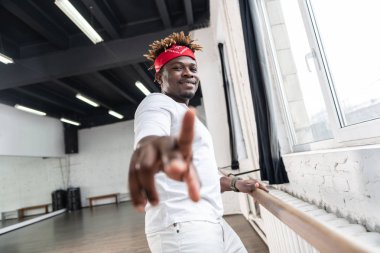 Ahşap stand üzerinde eğiliyor tüm beyaz kıyafeti sanatsal Afrikalı Amerikalı adam