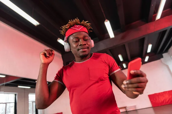 Sonriente chico de pelo corto con rastas mirando en la pantalla del teléfono inteligente — Foto de Stock