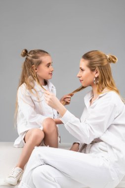 Birbirlerinin önünde oturan farklı çağların iyi görünümlü benzer kızlar