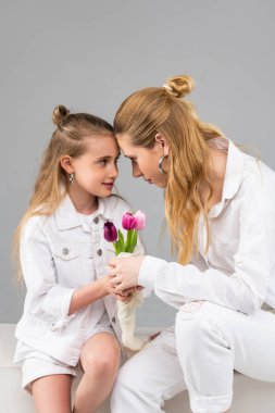 Uzun saçlı yetişkin kadın küçük arkadaşının gözlerine derinden bakıyor