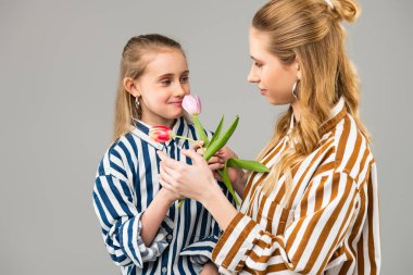 Parlak kıyafetler çiçek paylaşan uzun saçlı kusursuz bayanlar