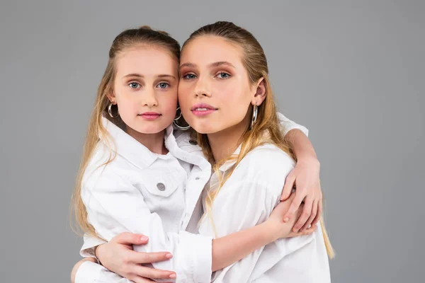 Hermanas jóvenes de pelo largo posando juntas sobre fondo gris —  Fotos de Stock