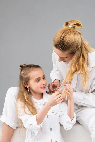 Long-haired curious child observing lighter hair of her elder sister