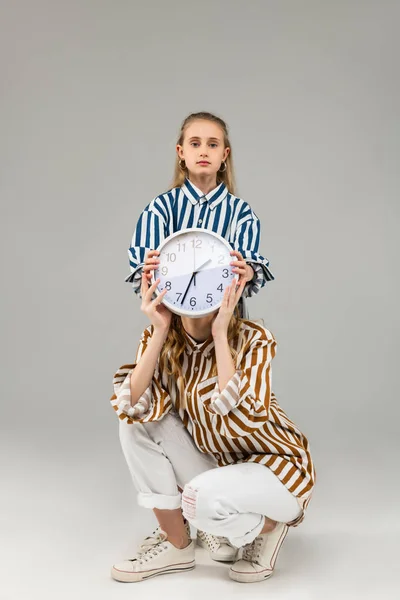 Serio niño de pelo largo que cubre la cara de la mujer adulta con el reloj llano —  Fotos de Stock