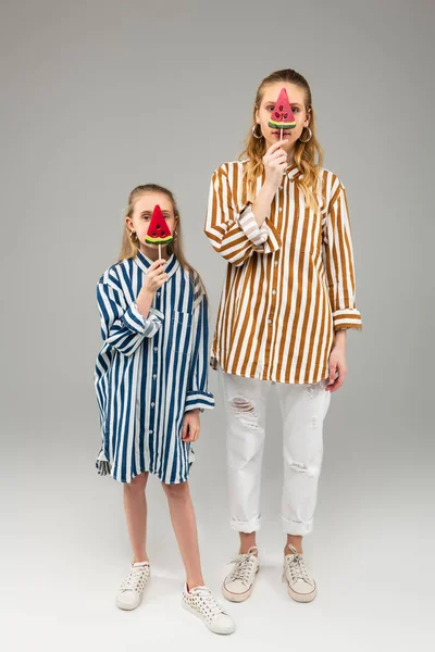 Good-looking long-haired girls in striped bright shirts holding watermelon shaped candy — Stock Photo, Image