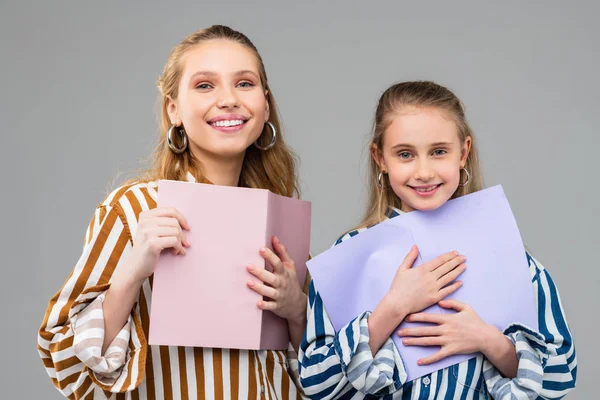 Smiling cheerful girls tightly carrying colorful papers — Stock Photo, Image