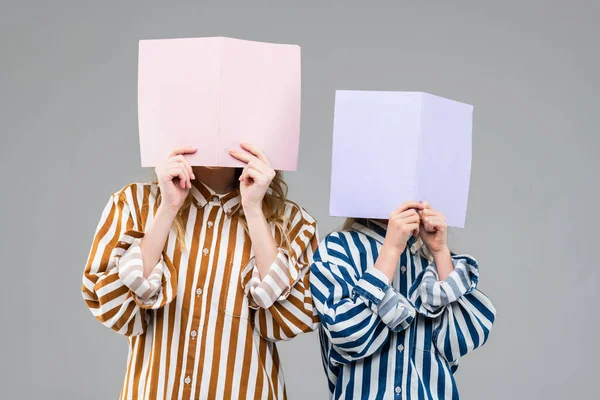 Girls in colorful striped oversize shirts covering their faces — Stock Photo, Image