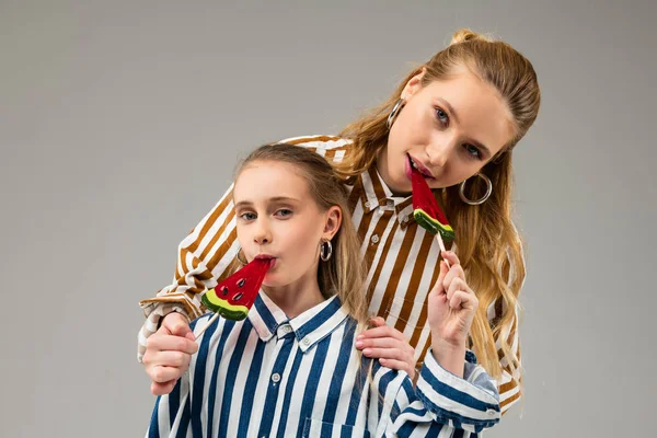 Pleasant satisfied good-looking girls in bright outfits eating candies — Stock Image Pleasant satisfied good-looking girls in bright outfits eating candies Royalty Free Stock Photos