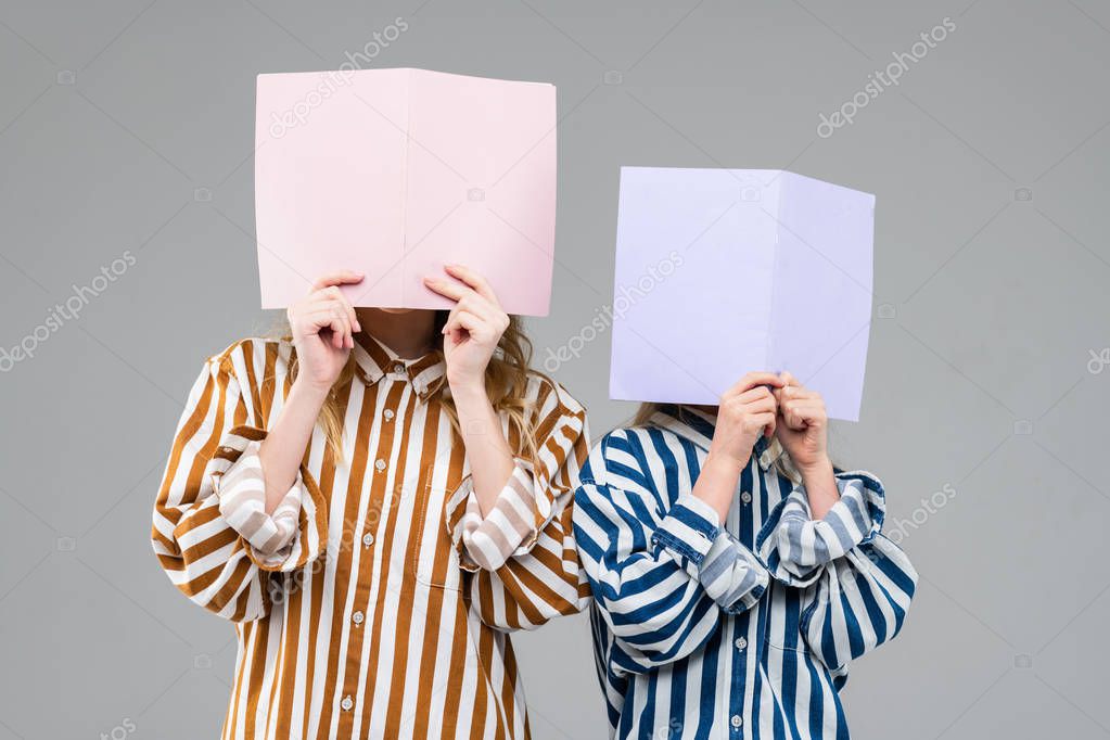 Girls in colorful striped oversize shirts covering their faces