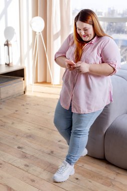 Neşeli tombul kadın akıllı telefona bakıyor